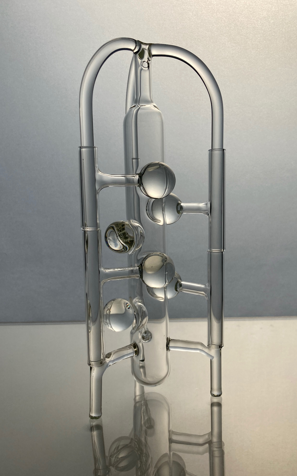 A complex glass piece, consisting of a central column surrounded by a tripod. Each column holds two rotating pieces with a glass sphere that reaches the central column.